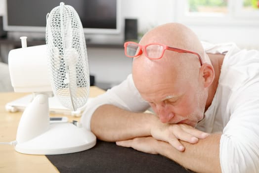 mature man refreshed with a fan in his home