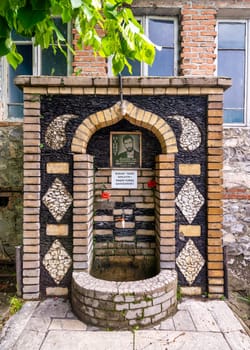 Shaki, Azerbaijan - May 15, 2024: A memorial drinking fountain features a portrait of a fallen soldier surrounded by decorative stones. It serves as a tribute to those who lost their lives in the war