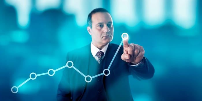 Mature business man is marking a growth trend in a line chart via touch on a virtual screen. Concentrated look, confident facial expression. Highly focused and energetic hand gesture. Copy space.