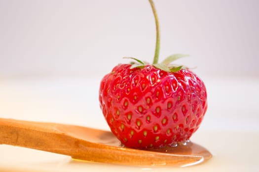 Strawberry in wooden spoon and honey