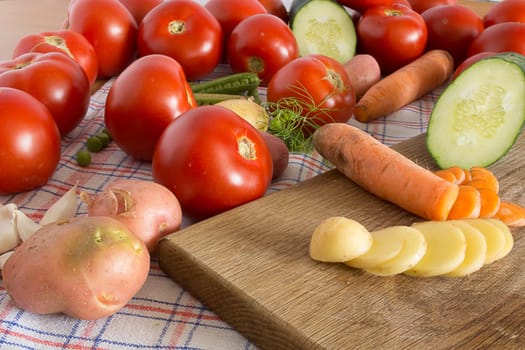 Sliced vegetables on a wooden plate in the kitchen