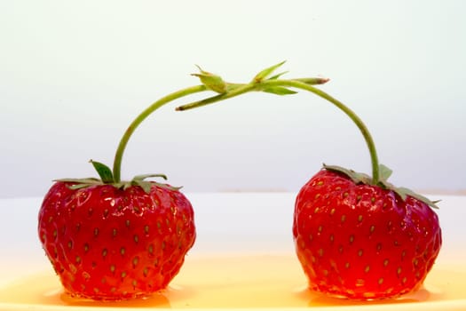 Strawberries in love hugging in plate full of honey