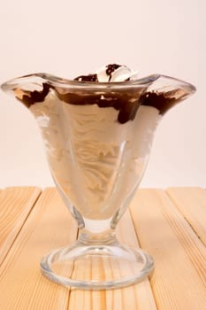 Glass cup with mixed vanilla and chocolate on white background, standing on wooden table