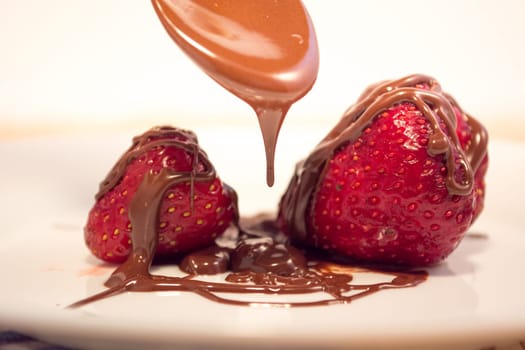 Plate with poured chocolate over strawberry
