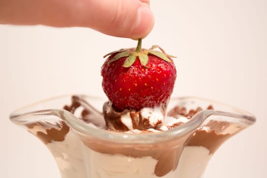 Glass cup with mixed vanilla and chocolate with strawberry being picked up