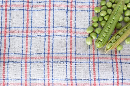 Green beans on a kitchen table covered with the rag in the corner of a shot.