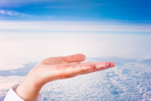 Open palm of left hand of a male white collar professional high above a dense cloud formation is offering empty copy space. Close up of human hand is shot under studio conditions. Business concept.
