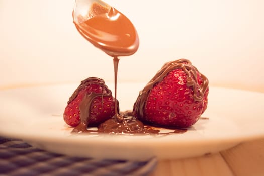 Plate with poured chocolate over strawberry