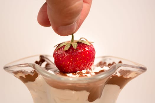 Glass cup with mixed vanilla and chocolate with strawberry being picked up