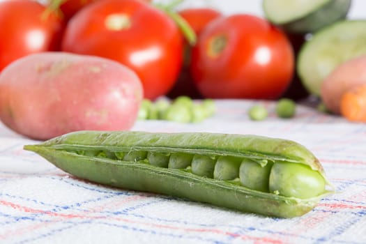 Green beans on a kitchen table with blurred background with other vegetables