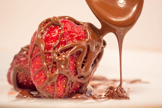 Plate with poured chocolate over strawberry