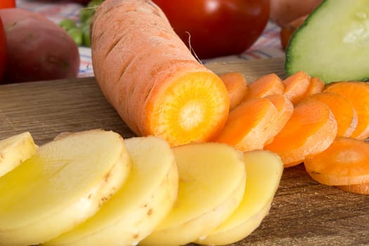Sliced potato and carrot on a wooden plate in the kitchen