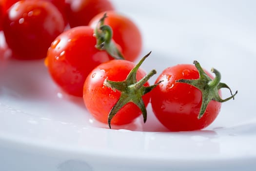 Ripe and red cherry tomatoes in white plate isolated on white background
