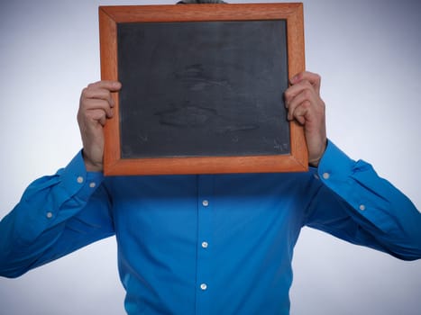Businessman hiding his face behind a small chalkboard with space for text or image