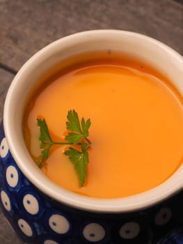 Closeup of a pumpkin cream soup in a rustic bowl