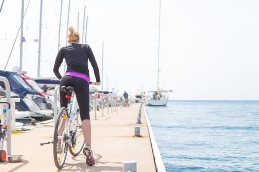 Young active woman cycling on pier in Rovinj marina, Istria, Croatia