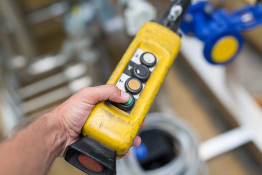 Industrial worker pushing on button of machinery control panel in manufactury.