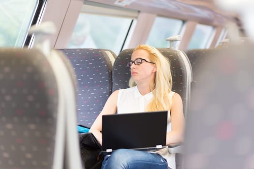 Businesswoman naping sitted while traveling by train and working on laptop. Tiresome business travel.