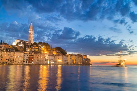 Coastal town of Rovinj, Istria, Croatia in sunset. Motion blur of sailing fishing boat can be seen on right side.
