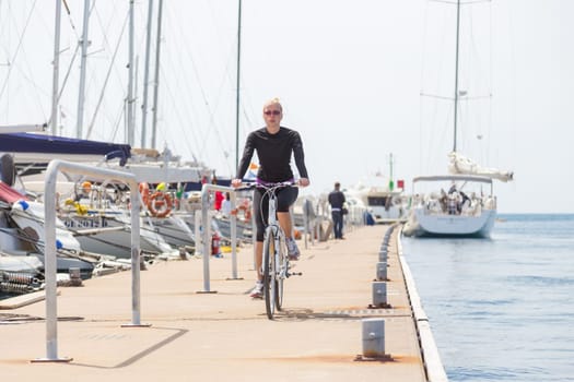Young active woman cycling on pier in Rovinj marina, Istria, Croatia