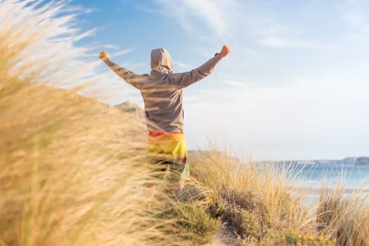 Successful sporty active man, arms raised, enjoying beauty of nature, freedom and life at beautiful landscape at Balos beach, Greece. Active lifestyle outdoors. Made it.