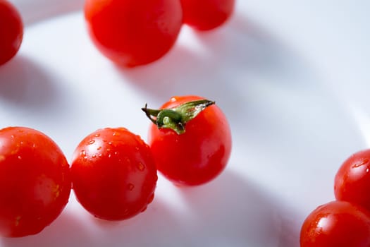 Ripe and red cherry tomatoes in white plate isolated on white background