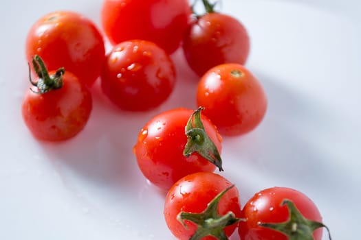 Ripe and red cherry tomatoes in white plate isolated on white background