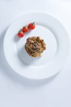 Ripe and red cherry tomatoes with zucchini muffins in white plate isolated on white background