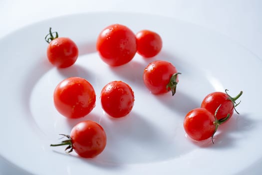 Ripe and red cherry tomatoes in white plate isolated on white background