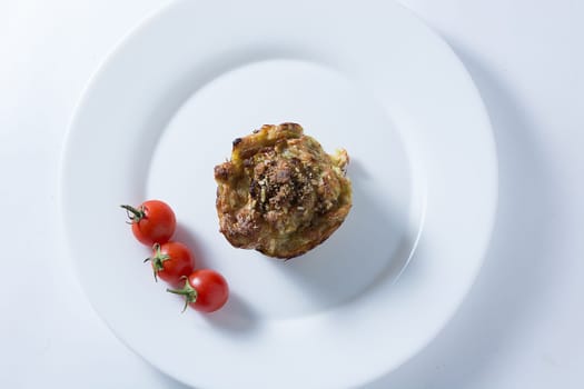 Ripe and red cherry tomatoes with zucchini muffins in white plate isolated on white background