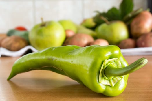 CLoseuo of the green pepper on the kitchen table with various vegetables in the background