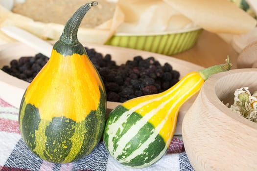 Decorative pumpkins on kitchen table with dryed chamomile in wooden bowl