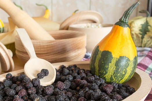 Chokeberry in small wooden plate with decorative pumpkin in it