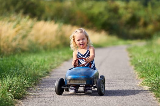laughing little girl with nostalgic pedal car