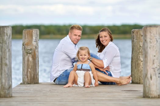 happy young family at the jetty on the lake