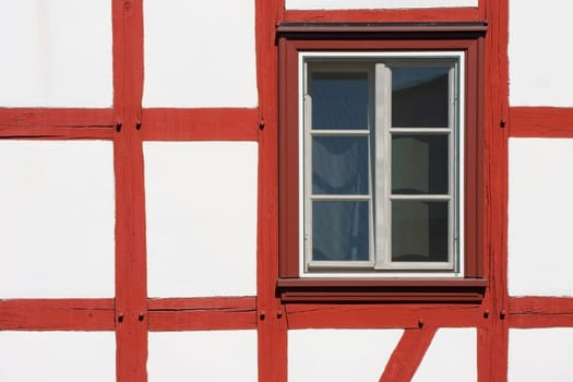 The close-up of the beam construction of a half-timbered house with window.