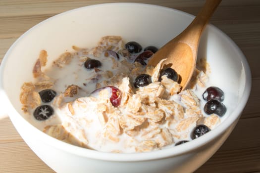 White bowl with healthy breakfast. Aronia and other berries with spelta  in milk