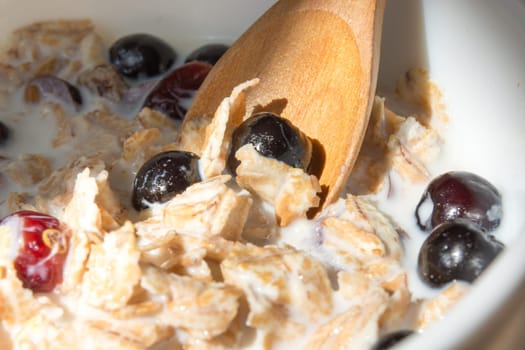 White bowl with healthy breakfast. Aronia and other berries with spelta  in milk