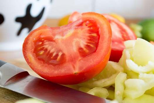 Kitchen full of various vegetables. Pepper, tomatoes sliced and ready to be boiled