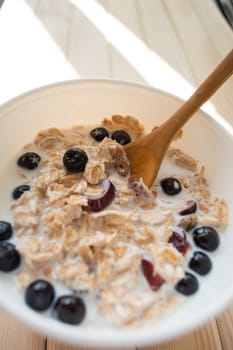 White bowl with healthy breakfast. Aronia and other berries with spelta  in milk
