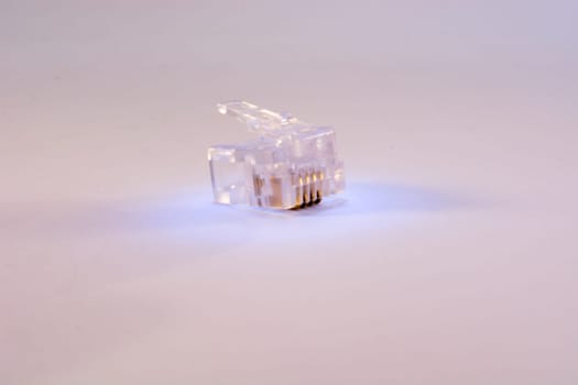 Single RJ-45 connector on white background. Connector is translucent and it is colored with blue light