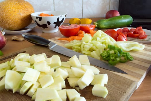 Kitchen full of various vegetables. Pepper, tomatoes sliced and ready to be boiled