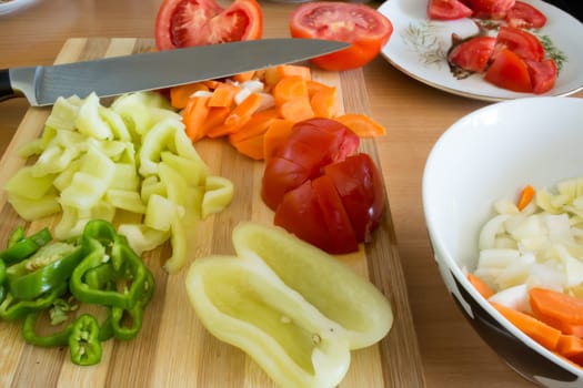 Kitchen full of various vegetables. Pepper, tomatoes sliced and ready to be boiled