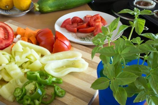 Kitchen full of various vegetables. Pepper, tomatoes sliced and ready to be boiled