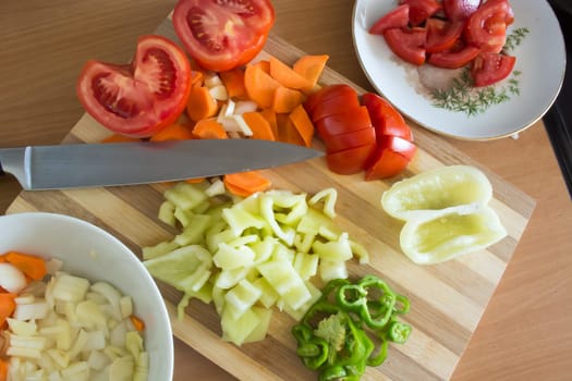 Kitchen full of various vegetables. Pepper, tomatoes sliced and ready to be boiled