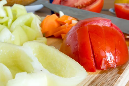 Kitchen full of various vegetables. Pepper, tomatoes sliced and ready to be boiled