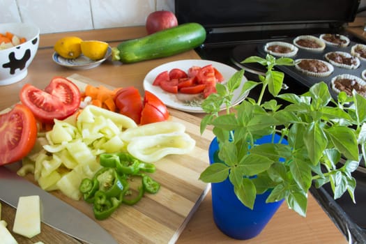 Kitchen full of various vegetables. Pepper, tomatoes sliced and ready to be boiled