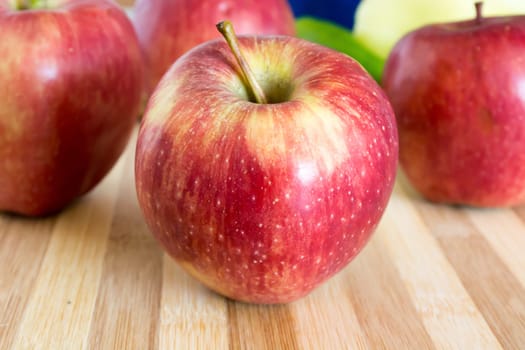Group of apples on wooden plate, ready to be sliced and eaten.