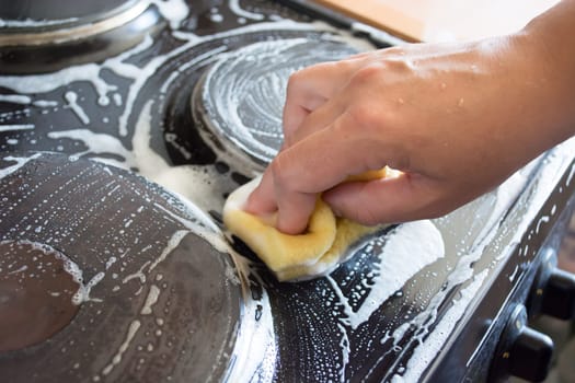 Close up of woman cleaning cooker at home kitchen
