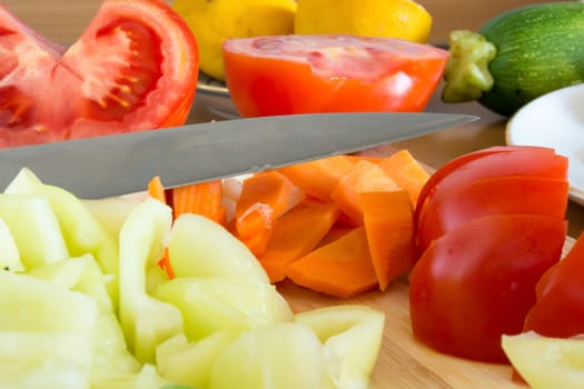 Kitchen full of various vegetables. Pepper, tomatoes sliced and ready to be boiled